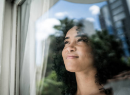 Woman looks out window with hopeful expression